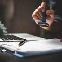 Man stamping approval of documents on desk.