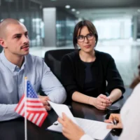 a-couple-sits-across-from-an-interviewer-in-a-modern-office-setting