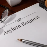 a-document-titled-asylum-request-on-a-wooden-desk-with-reading-glasses-and-a-pen-nearby
