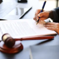 a-person-signs-a-contract-at-a-desk-with-a-pen