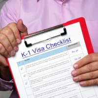 man-in-a-pink-shirt-holds-a-red-clipboard-with-a-k1-visa-checklist-document