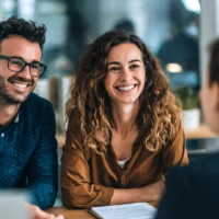a-smiling-couple-sits-at-a-desk-in-a-modern-office